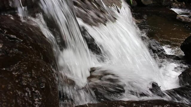 The view of the waterfall with rocks and clear water