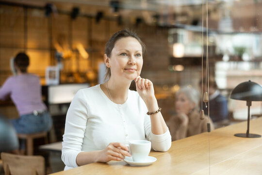 Portrait of young attractive girl drinking coffee in modern cafe