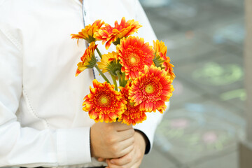 Bouquet of orange gerberas in the hands of a schoolboy. Return to school after holidays. Ceremonial start of the academic year.