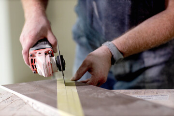 Professional tiler cutting tile with angle grinder. Construction, renovation, repair apartment.