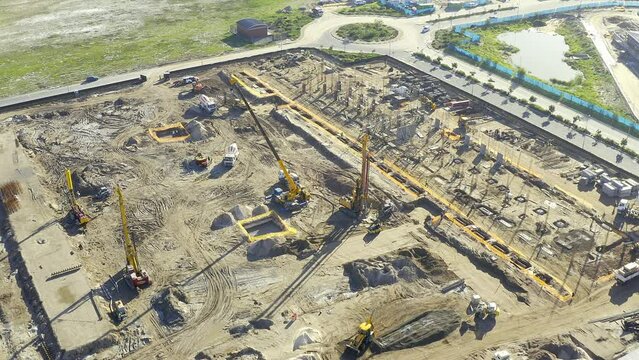 Crane, industrial and drone view of a construction site, building foundation or infrastructure development. Ground, landscape and areial of a field with machines for engineering or labour environment