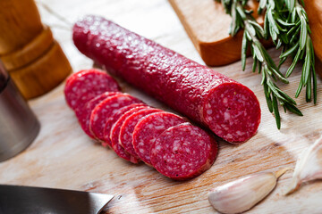 Traditional Spanish jerked sausage of Fuet Nobleza from minced pork seasoned with garlic and pepper with cut slices on wooden surface..