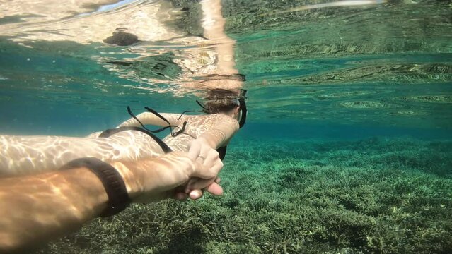 Scuba diving, swimming and people holding hands in ocean for adventure, holiday and vacation in Mauritius. Nature, travel and couple in tropical water for dive, coral reef and snorkeling on island