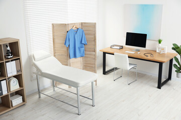 Modern medical office with doctor's workplace and examination table in clinic
