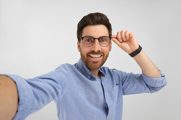 Fototapeta premium Smiling man taking selfie on white background