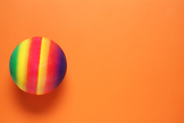 New bright kids' ball on orange background, top view. Space for text