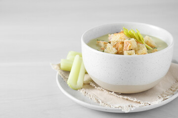 Bowl of delicious celery soup on white table, closeup. Space for text