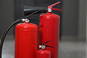 Obraz premium Three new red fire extinguishers in hall, closeup. Space for text