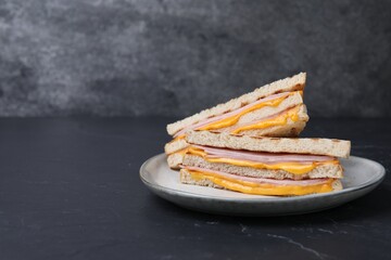 Delicious grilled sandwiches with ham and cheese on black table. Space for text