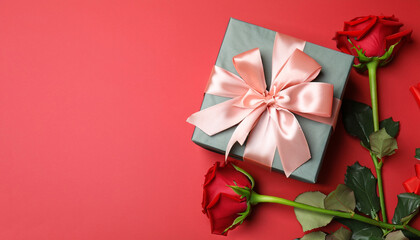 Beautiful gift box and roses on red background, flat lay with space for text. Valentine's day celebration