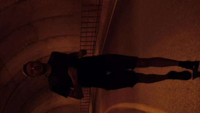 Portrait of man running in dark tunnel at night. Vertical video. Active sport
