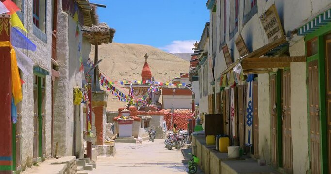 An alley in Upper Mustang Nepal has ancient stupa and Buddhist flags are flying all around. Beautiful alley road is seen peaceful and colourful. 4K