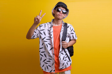 Confident young Asian tourist student man with backpack showing fingers doing victory sign. Number...