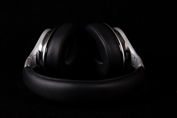 Black and silver headphones lays on black background.