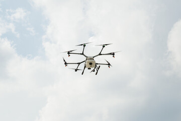Octocopter in the sky. Professional agriculture drone in cloudy sky. 