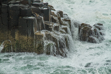 Water running off hexagonal basalt rocks on an island after a wave break on the East coast of Australia