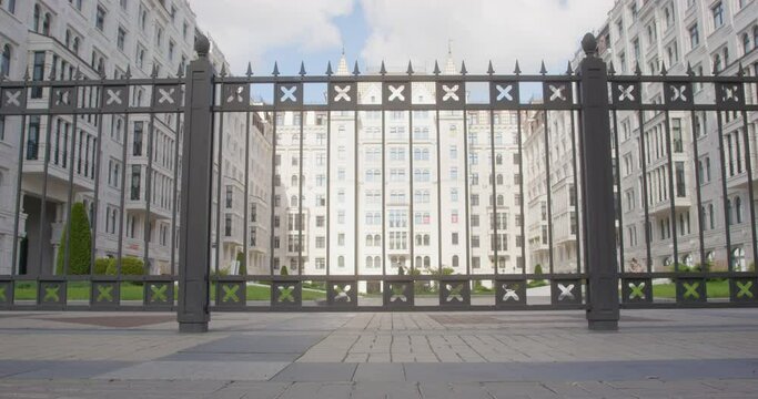 View through metal pattern of fence to closed courtyard of modern residential complex, with playground, cyclist child rides through safe protected area Infrastructure of apartment, comfortable housing