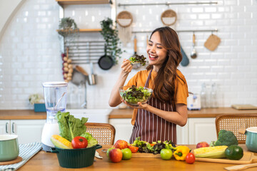 Portrait of beauty body slim healthy asian woman eating vegan food healthy with fresh vegetable salad in kitchen at home.diet, vegetarian, fruit, wellness, health, green food.Fitness and healthy food