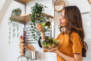 Portrait of beauty body slim healthy asian woman eating vegan food healthy with fresh vegetable salad in kitchen at home.diet, vegetarian, fruit, wellness, health, green food.Fitness and healthy food