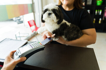 Happy woman paying with a credit card for dog grooming services