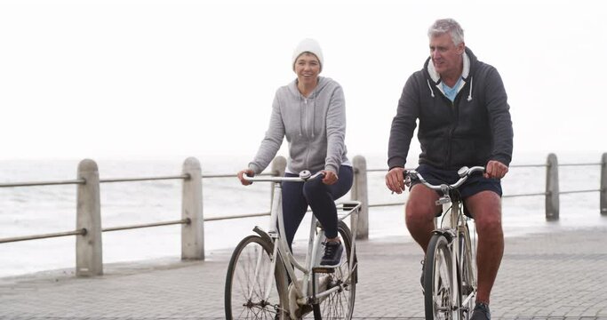 Senior Couple, Bicycle And Health At Beach For Exercise, Workout And Fitness On Winter Morning. Elderly Man, Old Woman And Cycling With Bike, Teamwork Or Talking Outdoor By Ocean, Nature And Wellness