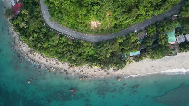 Azure ocean sand beach near hilly area with track for cars