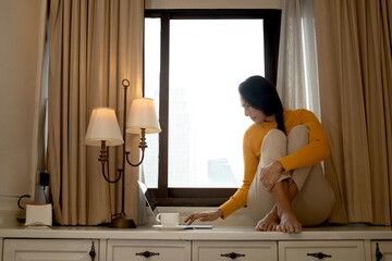 woman working from home Use a computer to sit by the window working on online project, searching...