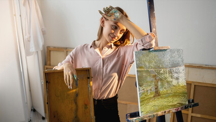 Nft painting. Crypto art. Blockchain technology. Satisfied tired female artist with glitch noise animated nature digital picture on canvas in studio.