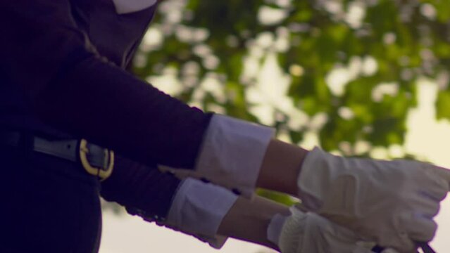 Cinematic close up shot of a woman riding a horse in slow motion with a black and white outfit and matching white gloves focusing on her face and body, Slomo