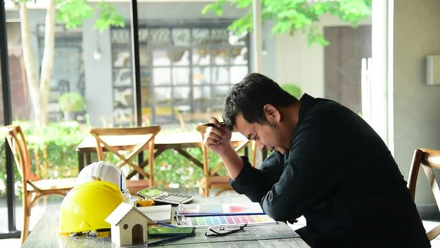 Asian young engineer man stress and failure in architecture project sitting at office on construction site. Upset despair civil construction engineer working on laptop with stressed problems 