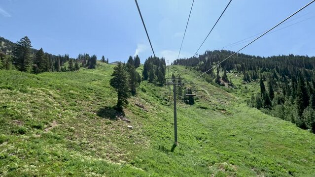 Mountain ski lift over green forest Utah. Summer and winter season mountain resort. Vacation nature family fun destination. Peaks and nature landscape forests. Rocky Mountains Salt Lake City Utah.