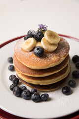 Pancakes stack with banana and blueberries topping and bee honey breakfast food