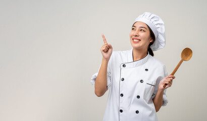 Young beautiful asian woman chef in uniform holding ladle utensils cooking in the kitchen various...