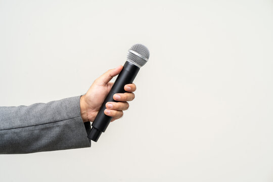 Close up businessman speaker hand holding High quality dynamic microphone and singing song or speaking talking with people on isolated white background. Male testing microphone voice for interview