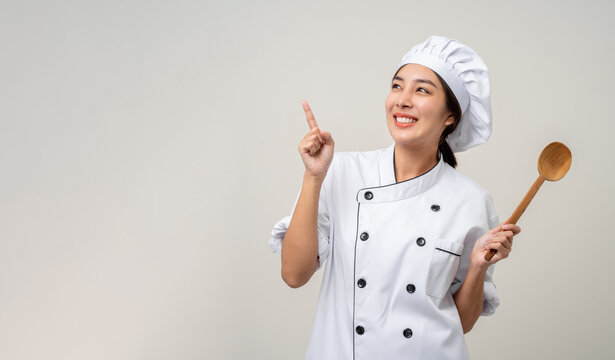 Young beautiful asian woman chef in uniform holding ladle utensils cooking in the kitchen various gesture delicious dish menu good taste on isolated. Cooking woman chef people in kitchen restaurant