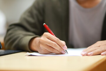 Smart young man reading documents while editing electronic versions on smartphone and laptop apps. Male freelancer working with documents and using technology
