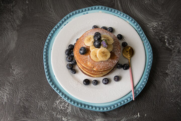 Pancakes stack with banana and blueberries topping and bee honey breakfast food