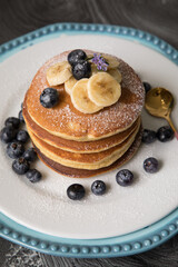 Pancakes stack with banana and blueberries topping and bee honey breakfast food