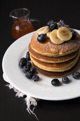 Pancakes stack with banana and blueberries topping and bee honey breakfast food