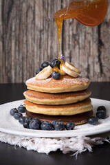 Pancakes stack with banana and blueberries topping and bee honey breakfast food