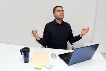 40-year-old Latino man breathes pranayama and practices yoga in his office to relax and de-stress...