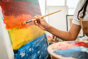 Close up hand Asian woman artist working on painting with brush and variant acrylic color. Female...