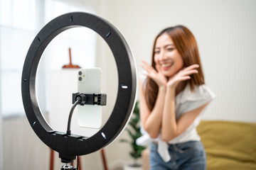 Fototapeta na wymiar Young trendy influencer asian woman dancing on mobile phone at home in living room. Creator vlogger talent dancing enjoy hobby content recording show video sharing on social media.