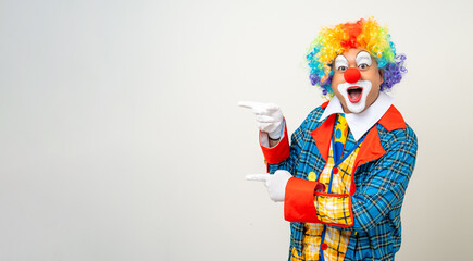 Mr Clown. Portrait of Funny comedian face Clown man in colorful uniform pointing finger to copy space for text advertise. Happy expression amazed male bozo in various pose on isolated background. - obrazy, fototapety, plakaty