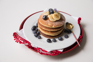 Torre de pancakes con arandanos y platano en plato blanco comida de desayuno