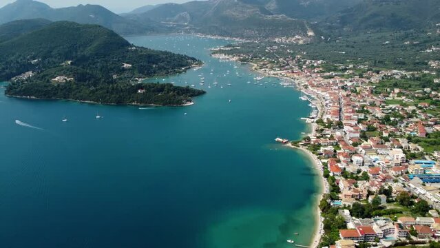 Aerial drone bird's eye view video of iconic port and city of Nidri or Nydri. Harbor for sail boats in Lefkada island, Ionian, Greece
