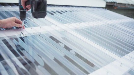 Screwing The Corrugated Polycarbonate Roof Sheets Of Greenhouse Garden. - closeup - Powered by Adobe