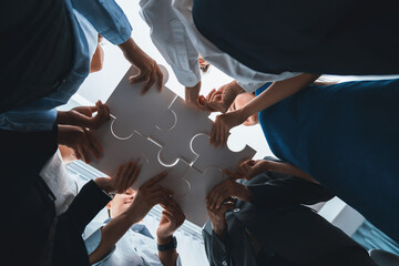 Below view of diverse corporate officer workers collaborate in office connecting puzzle pieces as...