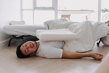 Asian man falling down from the bed lying on the floor at home.