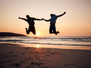 Beach, sunset and silhouette of couple jump, holding hands and enjoy fun quality time together on...